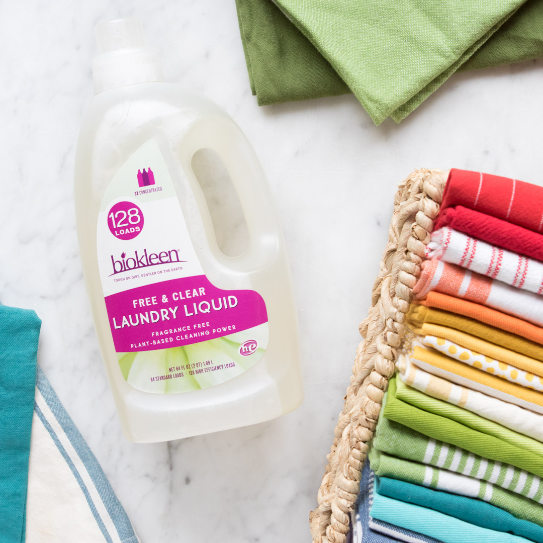 Biokleen Free & Clear plant-based laundry liquid beside a stack of folded linens on marble