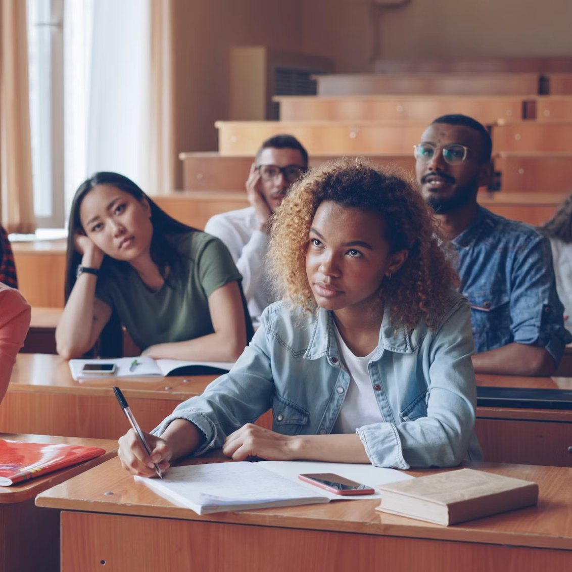 University students seated at lecture-hall desks taking notes during a class