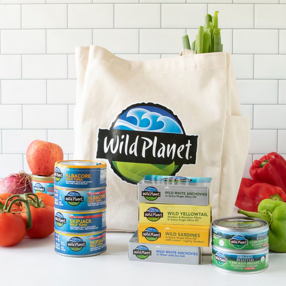 Wild Planet Foods canned tuna, sardines, anchovies and organic chicken arranged with fresh produce and a branded tote